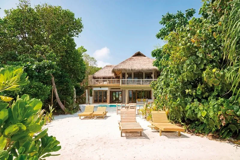Luksuzna vila na plaži Soneva Fushi s slamnato streho in ležalniki